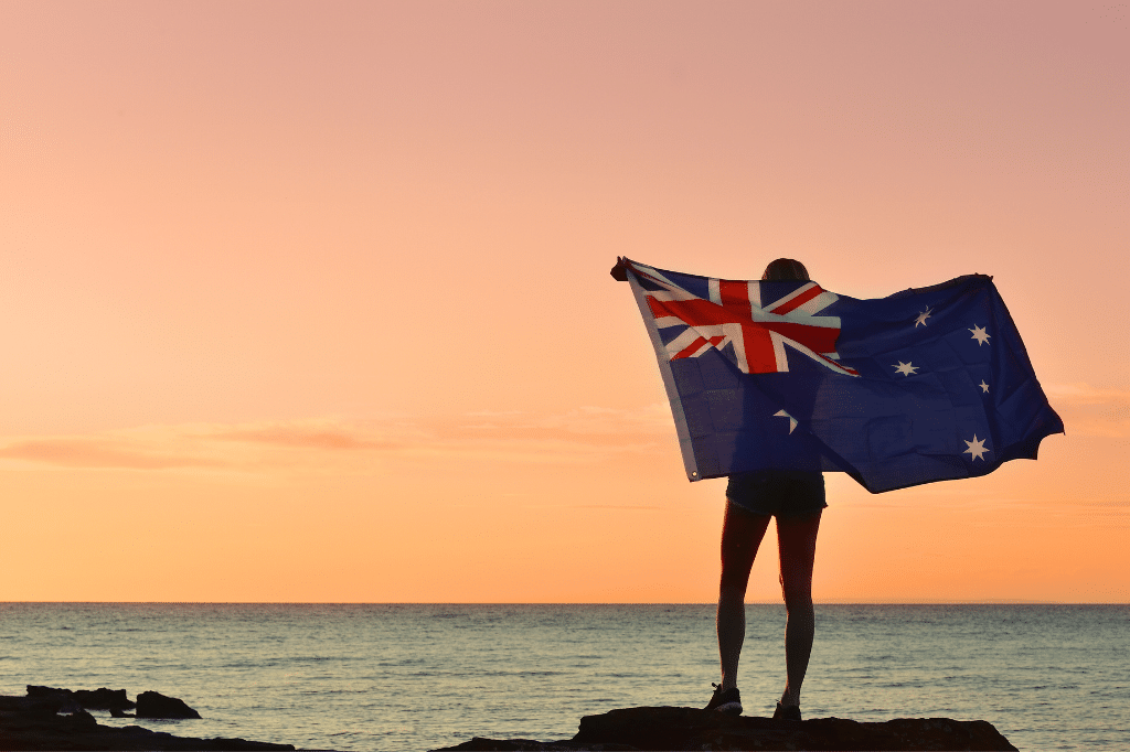 woman with australian flag standing by the beach at sunset